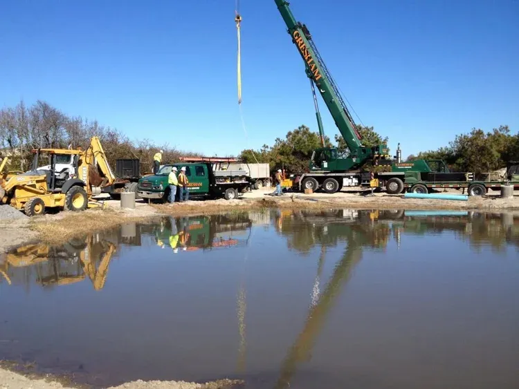 Crane, excavator and work trucks staged at a waterfront job site