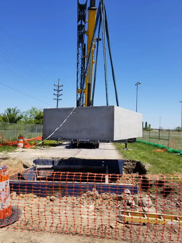 Crane setting heavy equipment on a prepared pad at an industrial site