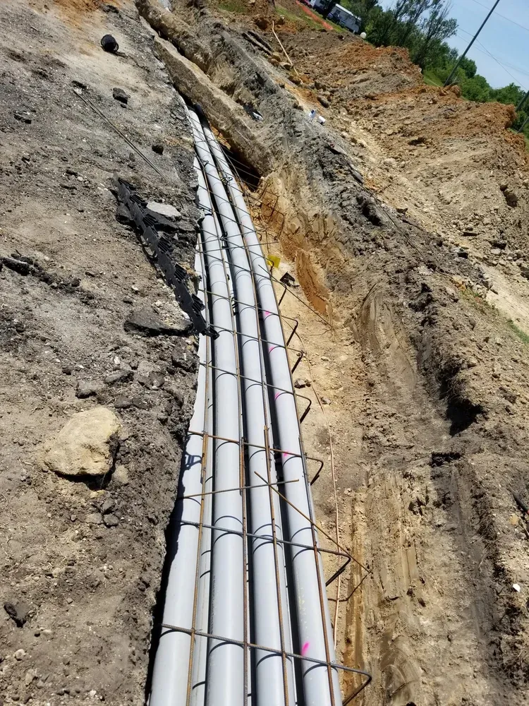 Bundled conduit running through a dirt trench